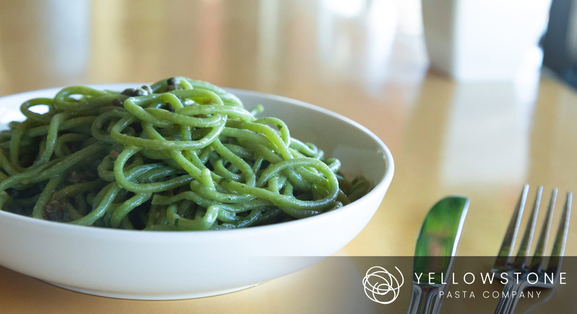 Product Photography for Yellowstone Pasta Company featuring Green pasta in a white bowl on table.